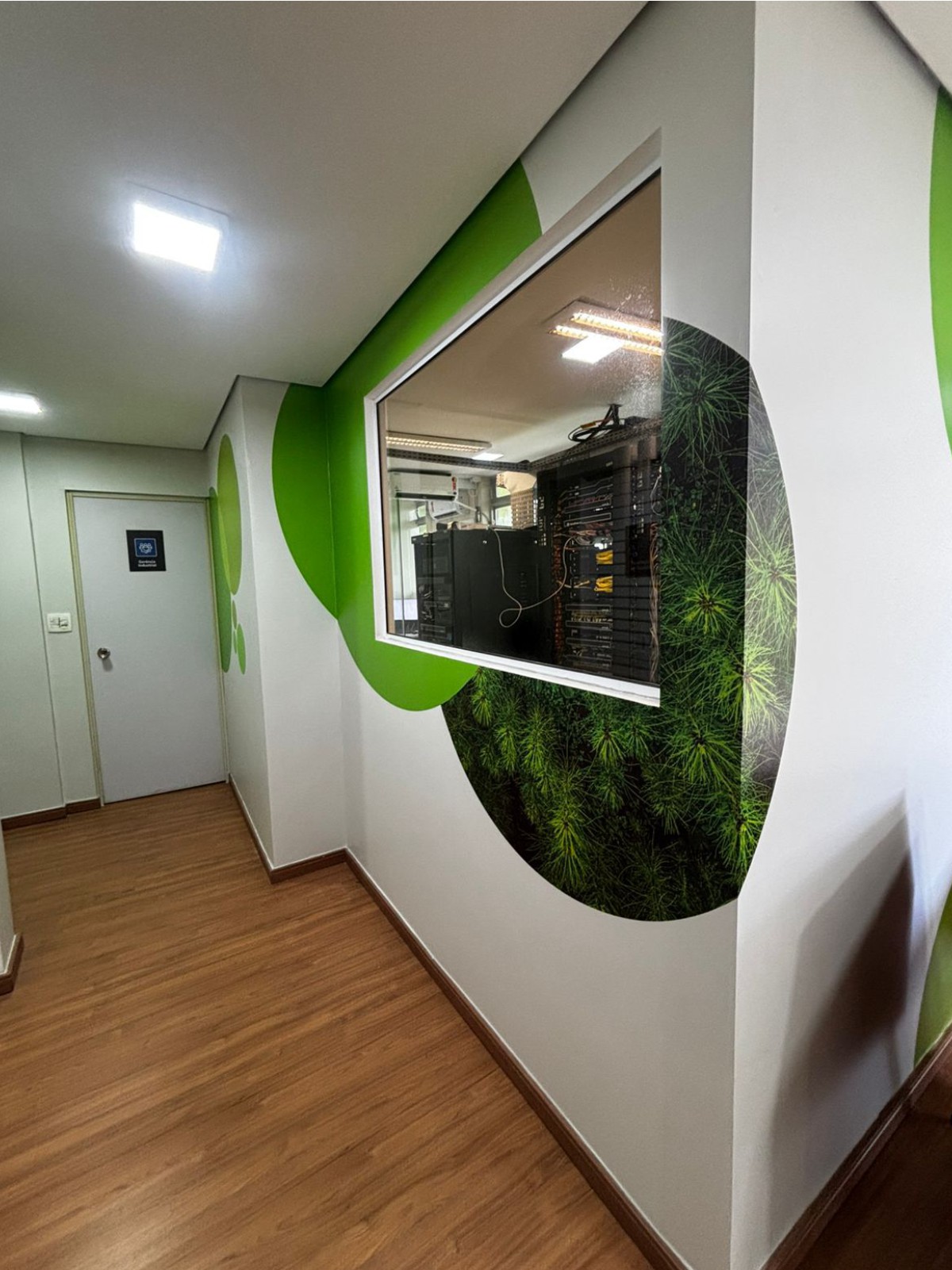 Ambientação de corredor com grafismo verde e janela de sala de servidores