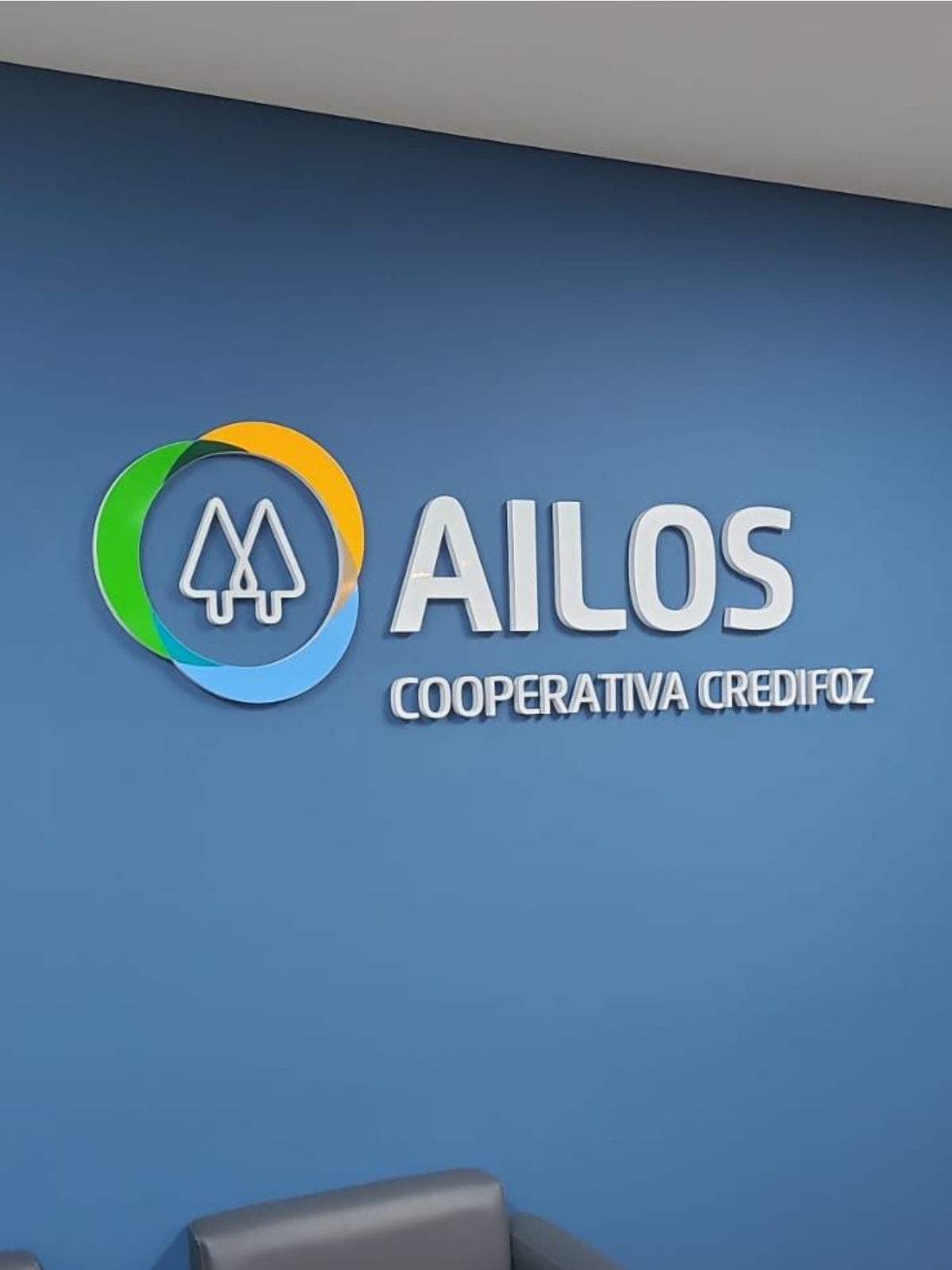 Letras caixa coloridas Ailos em parede azul